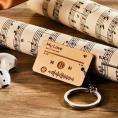 A wooden music card titled "My Love" on a wooden surface, accompanied by music sheets and earphones.
